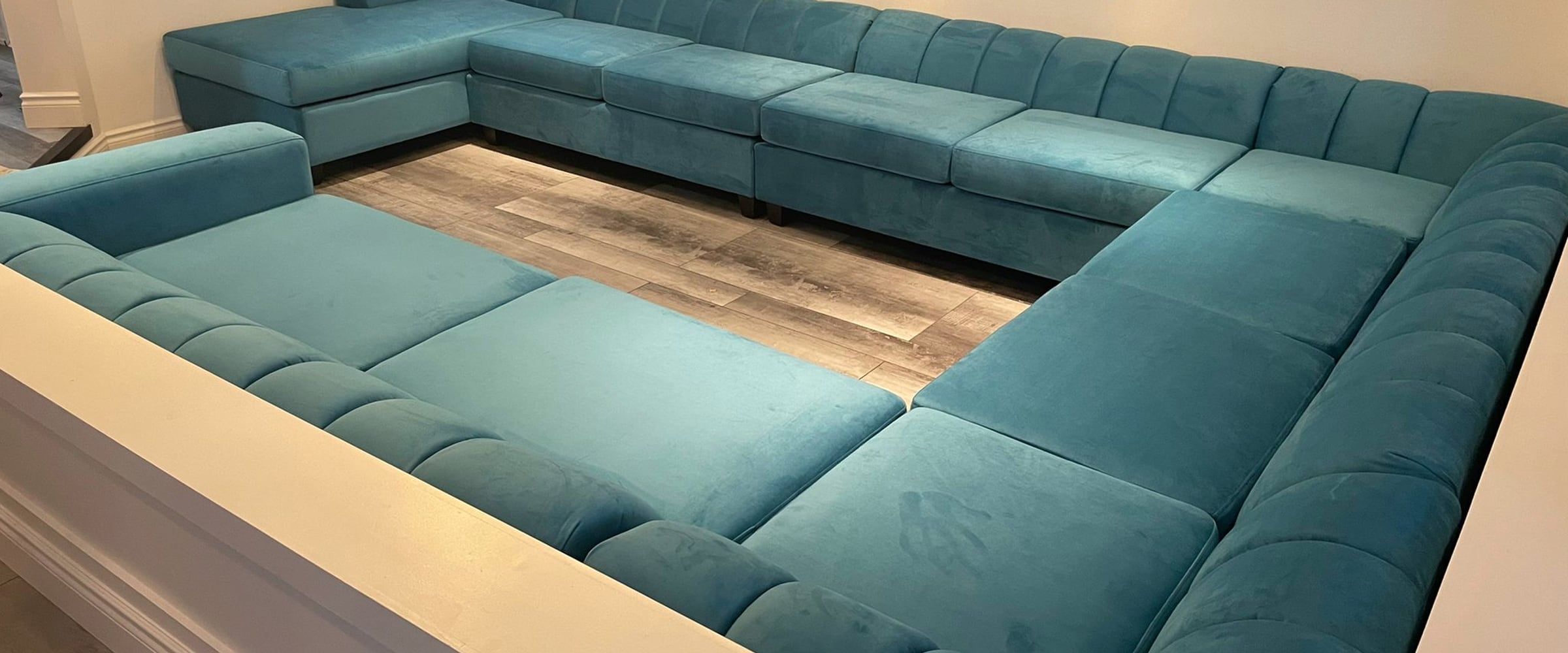 A twelve-seat teal velvet wraparound sectional built for a Brampton basement